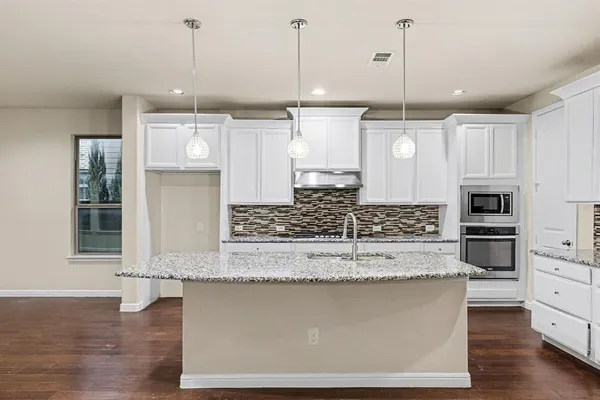 a large kitchen with kitchen island a stove a sink a counter space and wooden floor