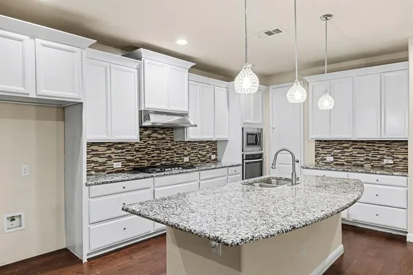 a kitchen with white cabinets and sink