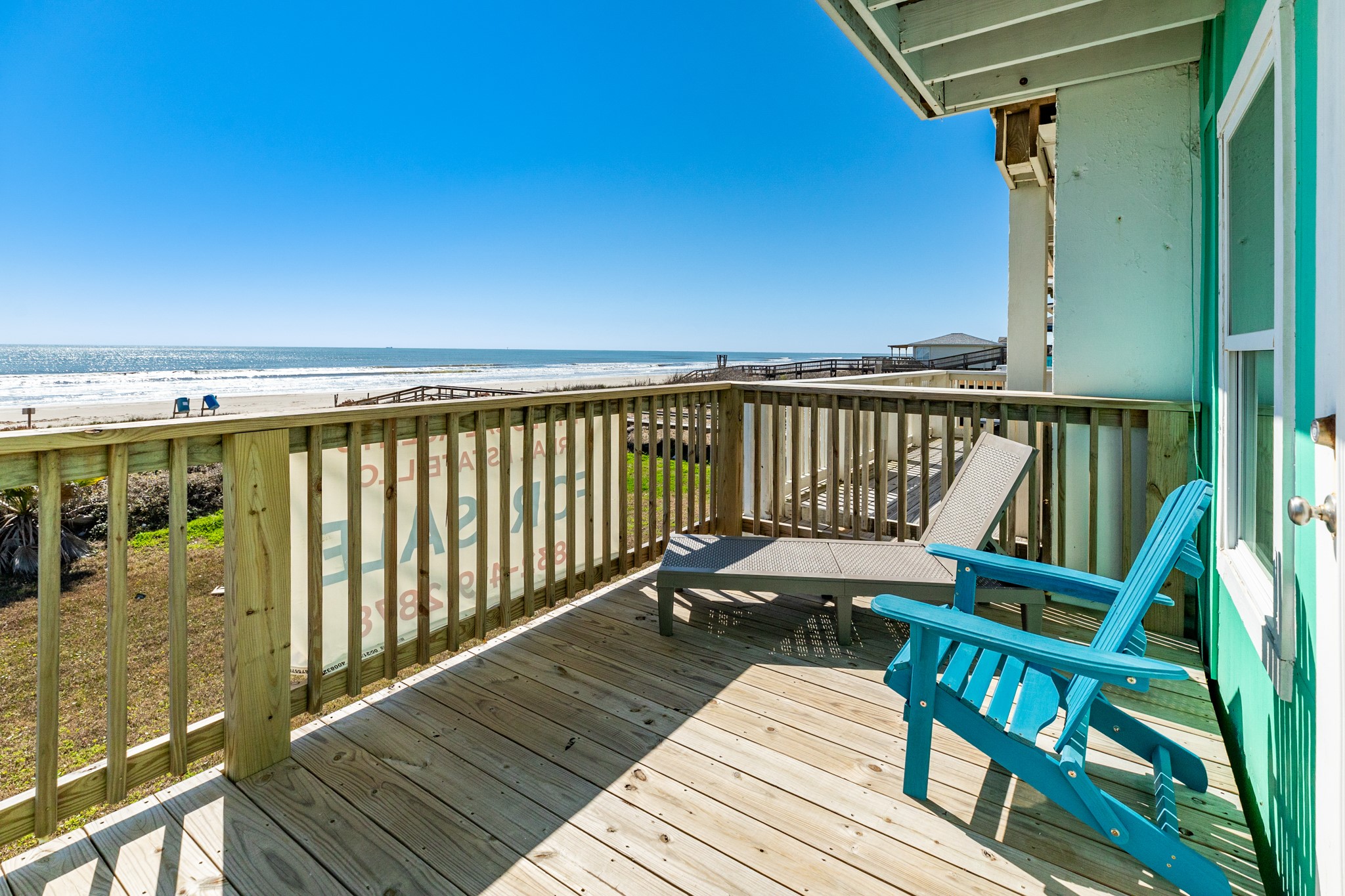101 Pelican Place, Unit 7 Freeport, TX 77541 - Photo 27 of 44 This photo features a beachfront deck with wooden flooring and a railing, offering stunning ocean views. It includes comfortable seating, ideal for relaxation and enjoying the scenery. The setting is bright and inviting, perfect for a seaside retreat.