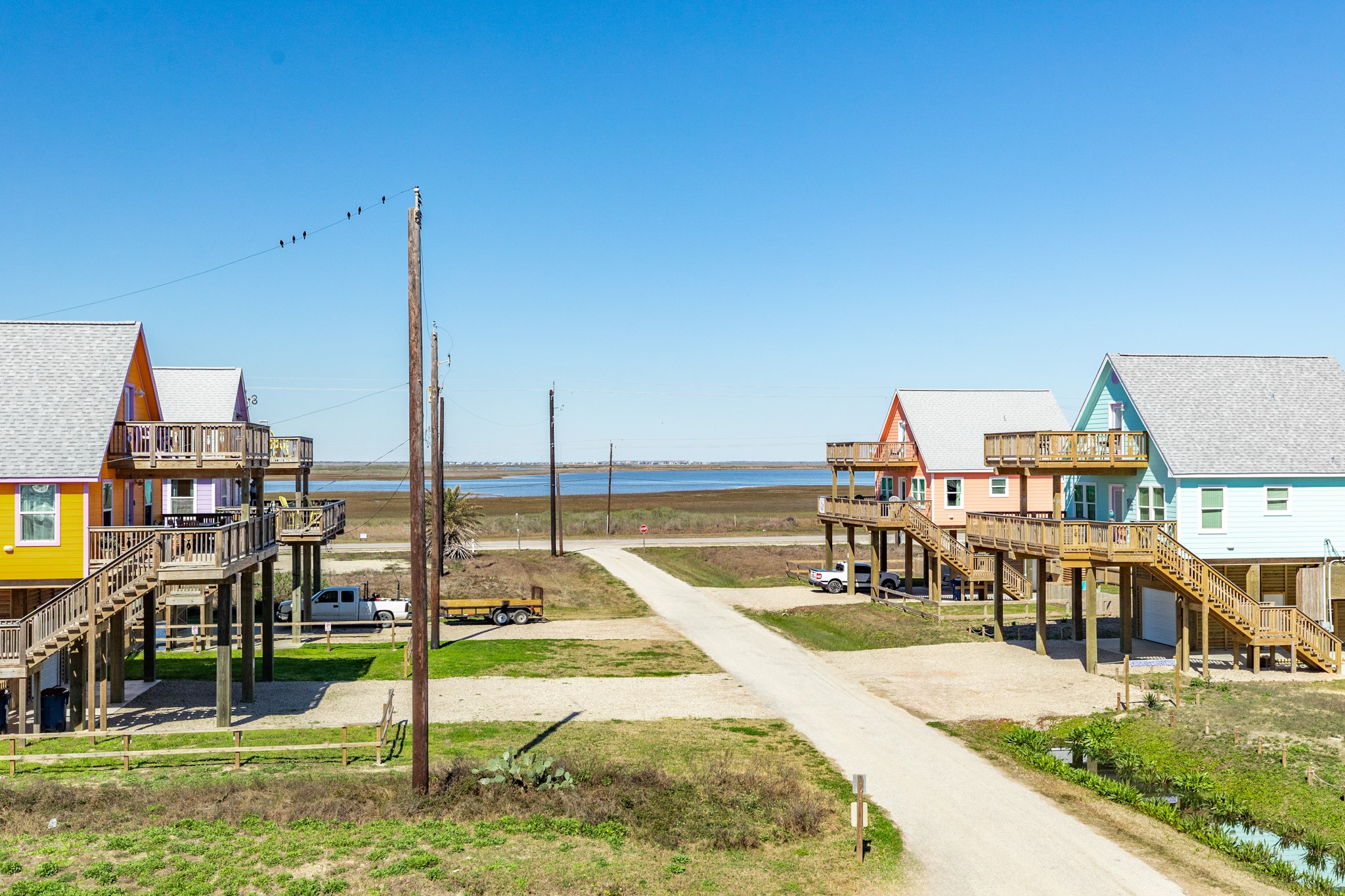 101 Pelican Place, Unit 7 Freeport, TX 77541 - Photo 36 of 44 This photo showcases colorful stilt houses in a coastal area, with a clear view of the water and open skies. Ideal for buyers seeking a vibrant, scenic, and elevated living environment near the coast.