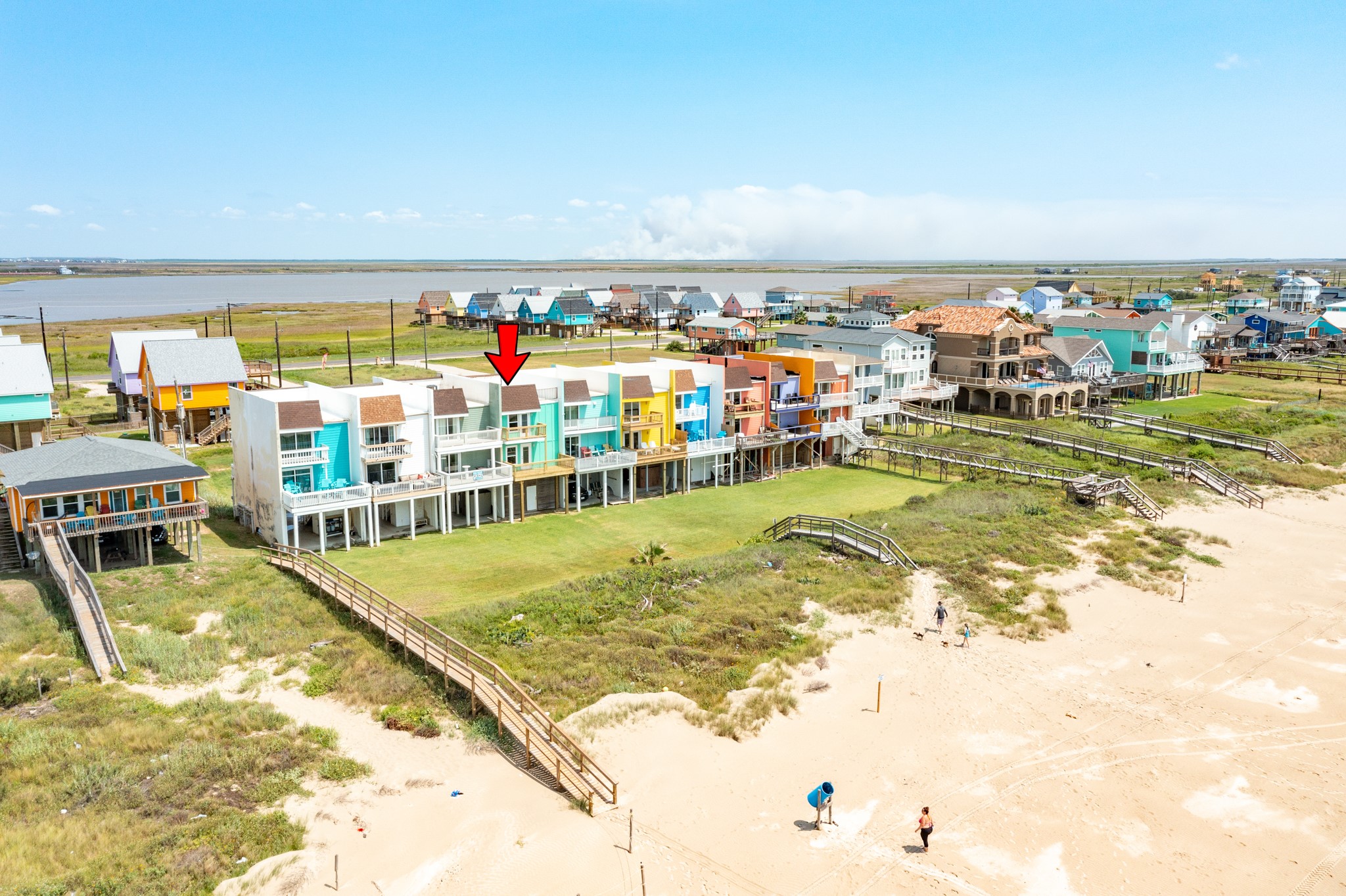 101 Pelican Place, Unit 7 Freeport, TX 77541 - Photo 41 of 44 This photo showcases a row of colorful beachfront homes with direct access to the sandy shore. The highlighted property offers stunning ocean views, spacious balconies, and a vibrant coastal community atmosphere. Ideal for beach lovers seeking a lively and picturesque setting.