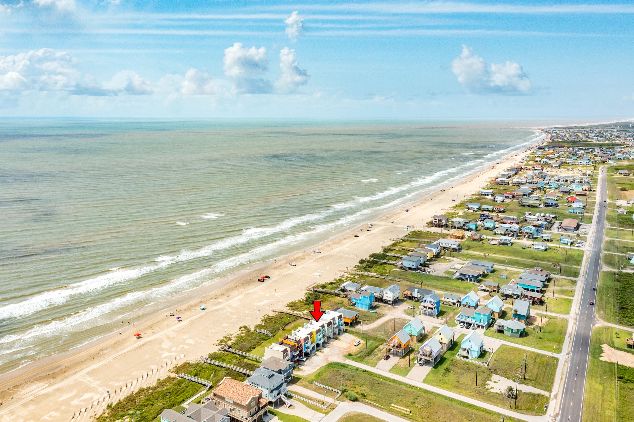 101 Pelican Place, Unit 7 Freeport, TX 77541 - Photo 42 of 44 This aerial photo showcases a beachfront community with colorful homes lining the coast. The property in question is near the water, providing direct beach access and stunning ocean views. Ideal for those seeking a serene coastal lifestyle.
