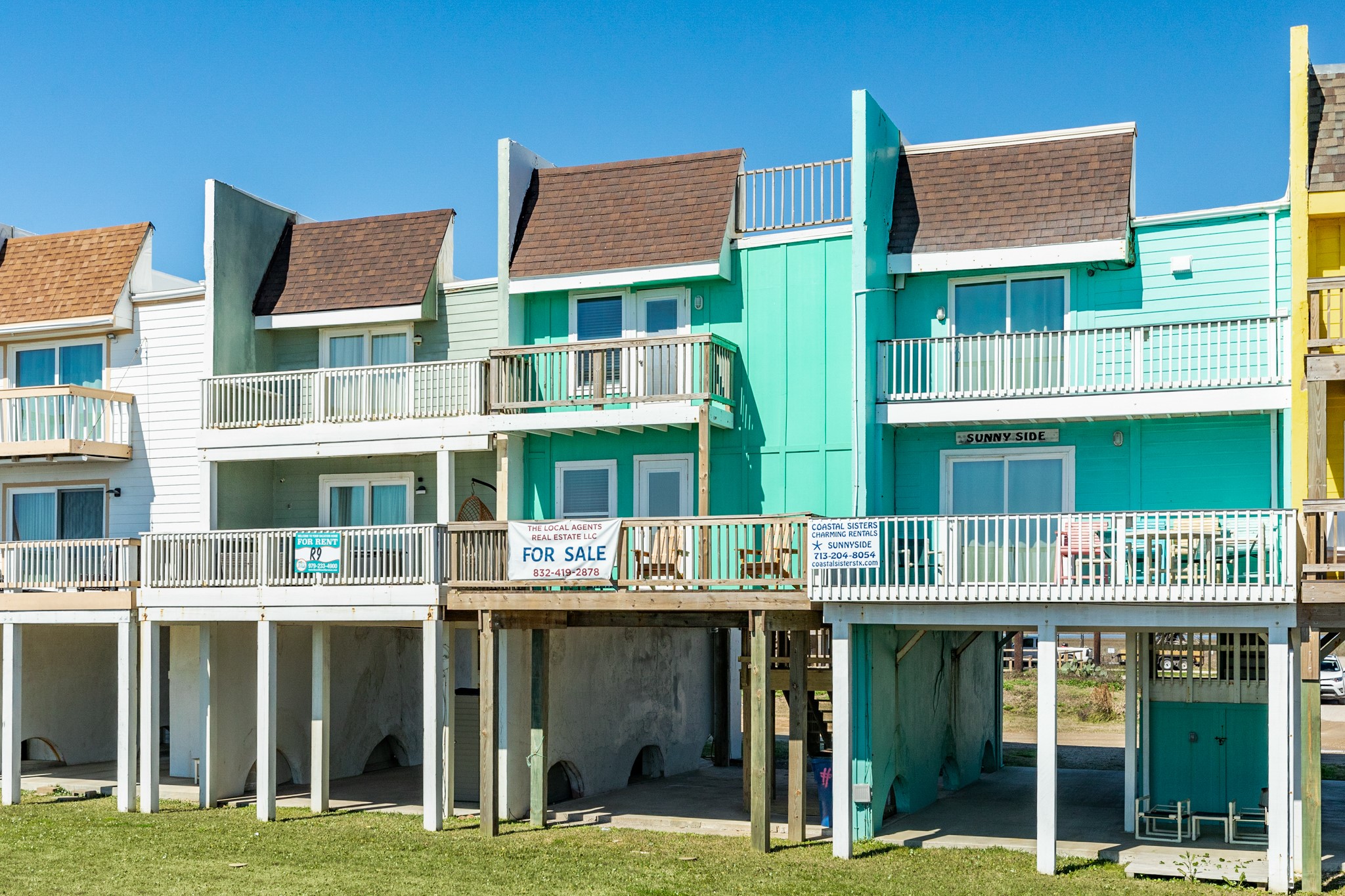 101 Pelican Place, Unit 7 Freeport, TX 77541 - Photo 6 of 44 Colorful beachfront townhouses on stilts with multiple balconies, offering coastal views. Each unit features a modern design, perfect for enjoying seaside living.