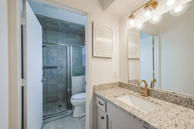 a bathroom with a granite countertop sink toilet and shower