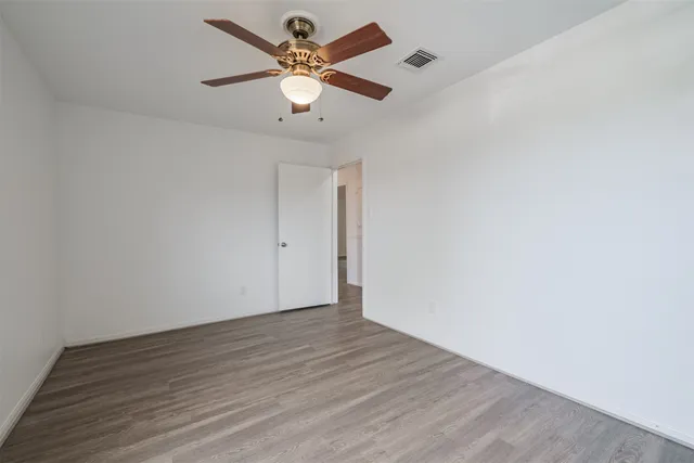 an empty room with wooden floor and a ceiling fan