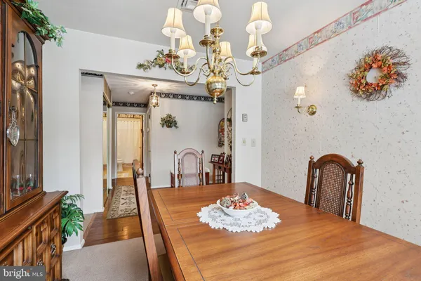 a dining room with wooden floor a chandelier a wooden table and chairs