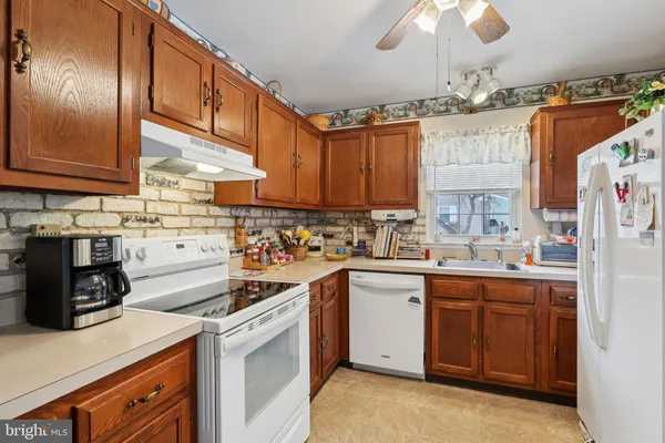 a kitchen with a sink dishwasher and white cabinets with wooden floor