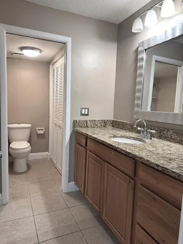 a bathroom with a granite countertop sink a toilet and a mirror