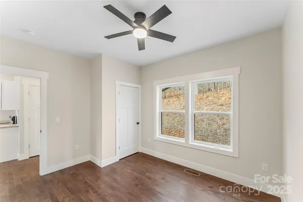 a view of an empty room with wooden floor and a window