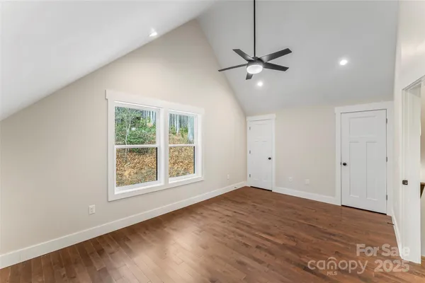 a view of an empty room with a window and wooden floor