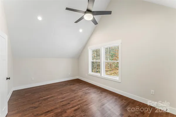 an empty room with wooden floor ceiling fan and windows