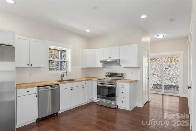 a kitchen with stainless steel appliances granite countertop a stove a sink and white cabinets