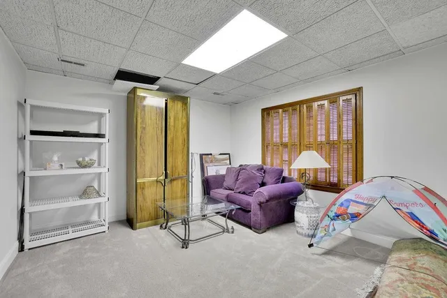 a view of a white house next to a yard with a large tree