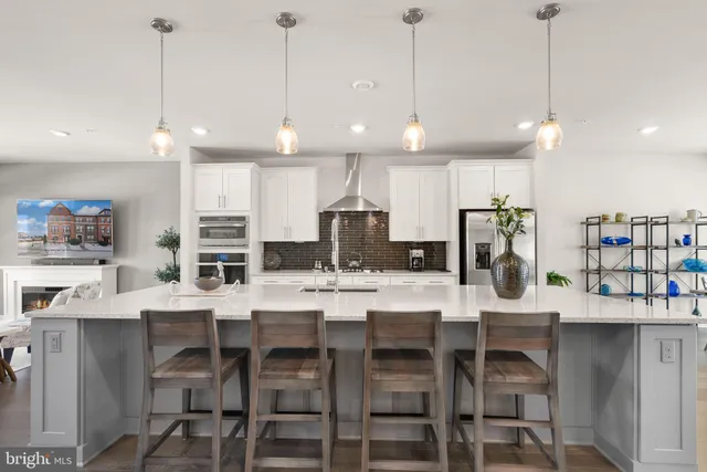 a kitchen with stainless steel appliances kitchen island granite countertop a dining table chairs and white cabinets