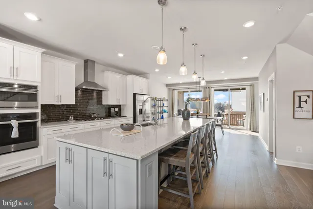 a kitchen with stainless steel appliances a dining table chairs refrigerator and microwave