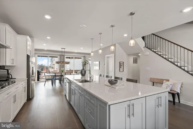 a kitchen with stainless steel appliances kitchen island granite countertop a sink dishwasher a stove a dining table and chairs with wooden floor