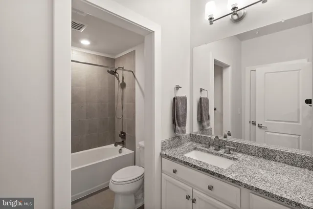 a bathroom with a granite countertop tub sink toilet and mirror