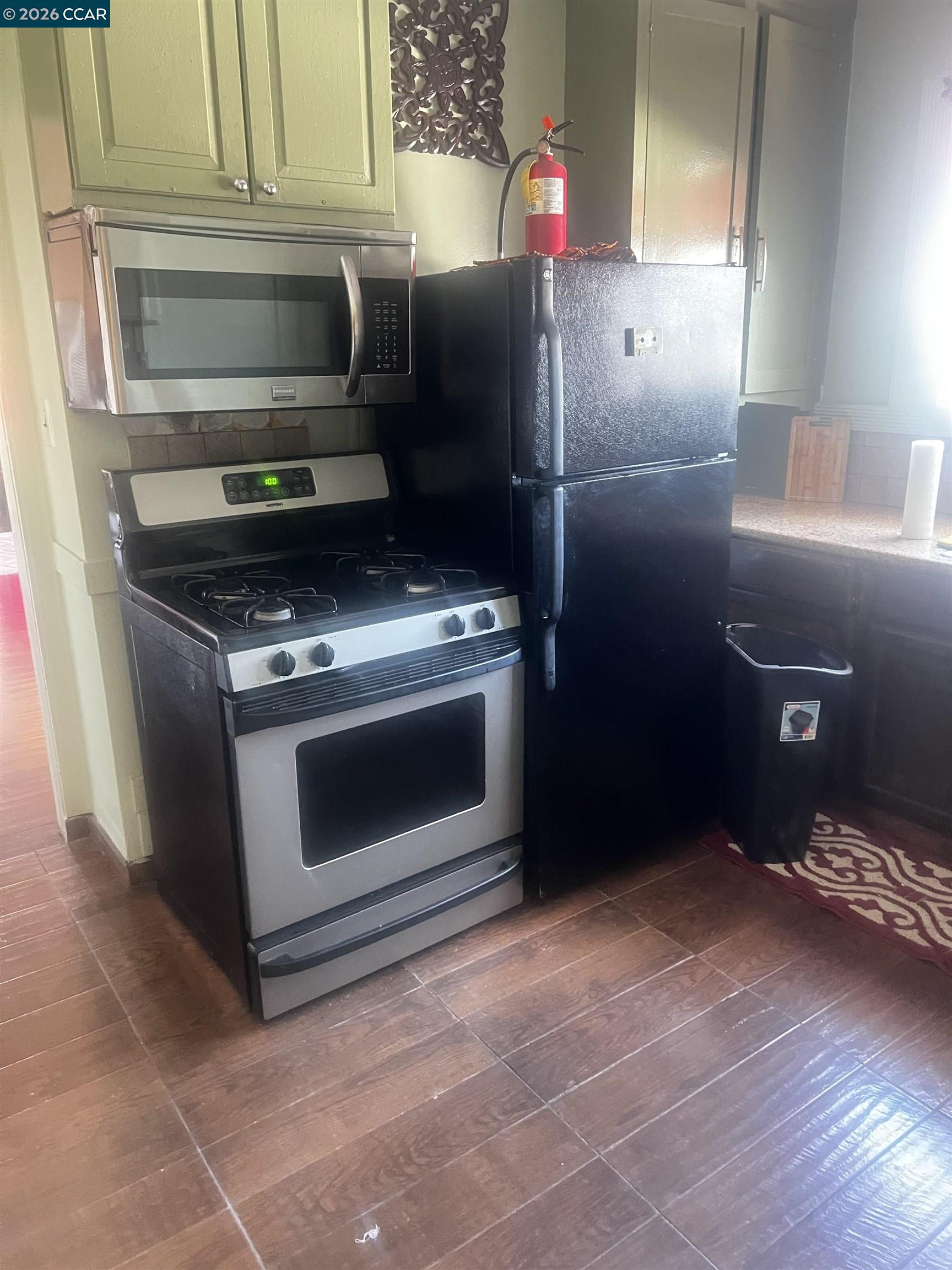 1161 64th Street Oakland, CA 94608 - Photo 23 of 25 a kitchen with granite countertop a stove and a microwave
