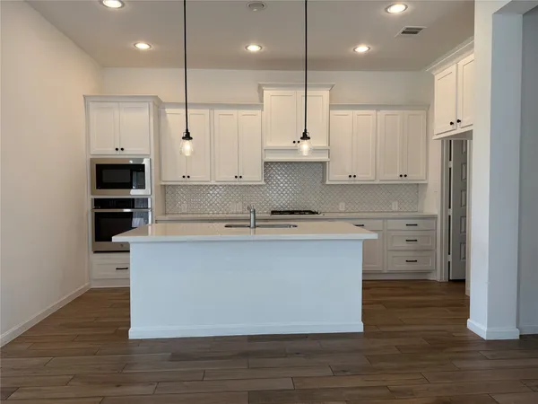 a large kitchen island with cabinets wooden floor and a window