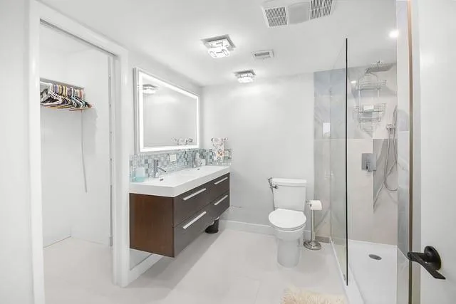 a bathroom with a sink a toilet a mirror and shower