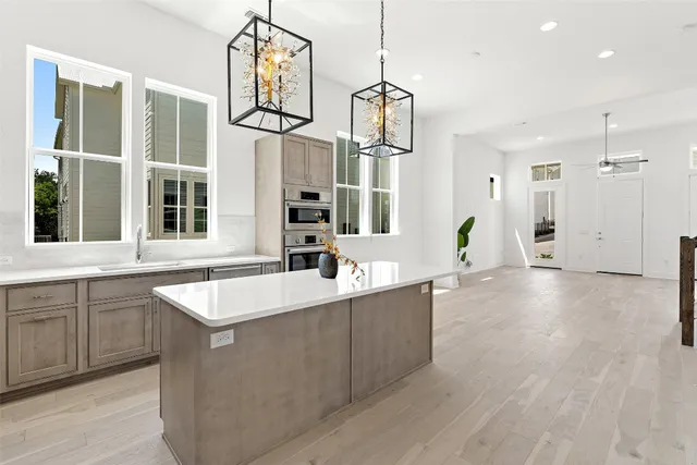 a large kitchen with stainless steel appliances a large counter top a sink and a window