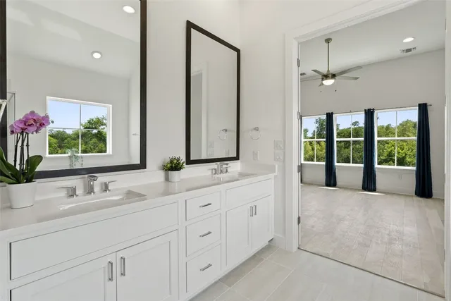 a bathroom with double vanity sink a two mirror a window and a bathtub