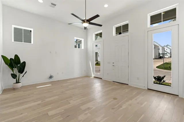 an empty room with wooden floor and ceiling fan