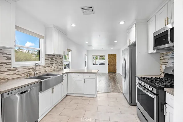 a kitchen with stainless steel appliances a sink stove top oven and refrigerator