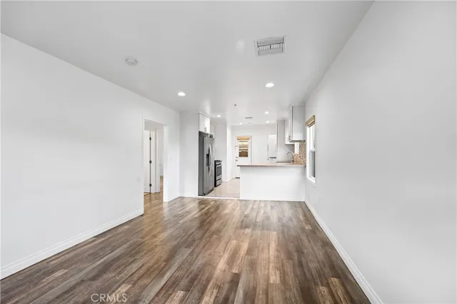 a view of a kitchen with refrigerator and wooden floor