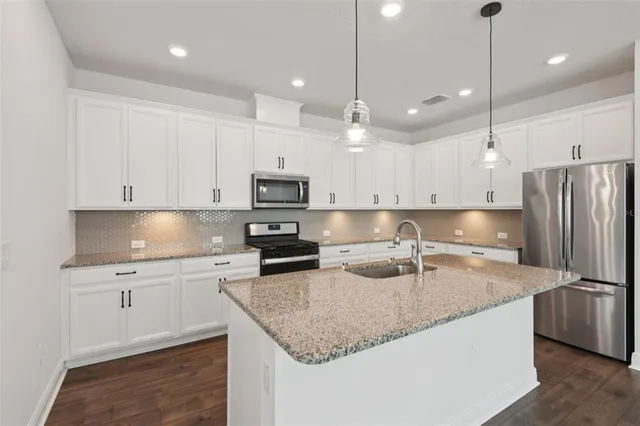 a kitchen with stainless steel appliances granite countertop a sink a stove and a refrigerator