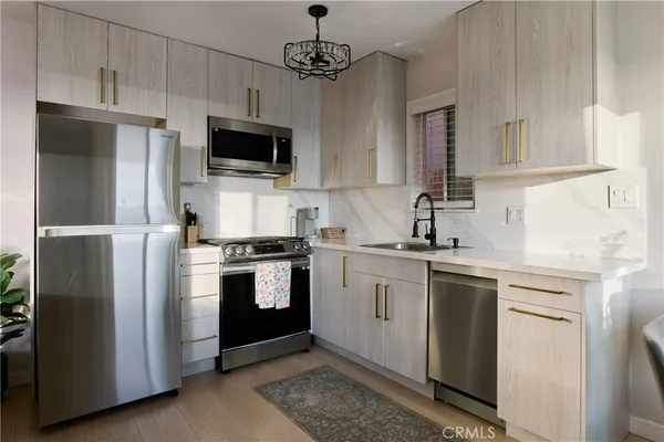a kitchen with stainless steel appliances granite countertop a refrigerator a sink a stove a microwave and wooden cabinets