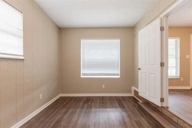 an empty room with wooden floor and windows