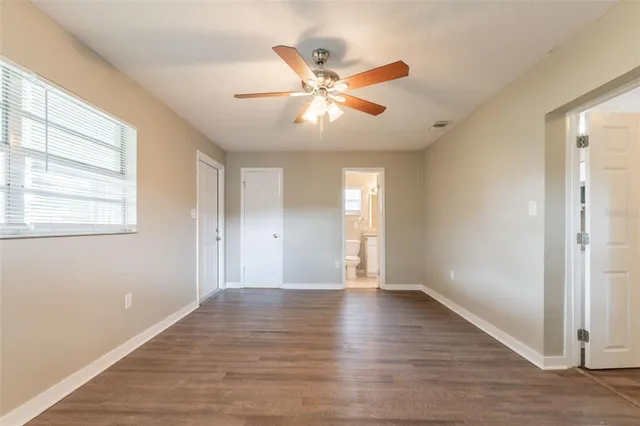 a view of an empty room with window and wooden floor