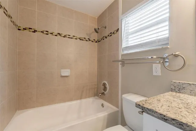 a bathroom with a granite countertop bathtub shower and sink