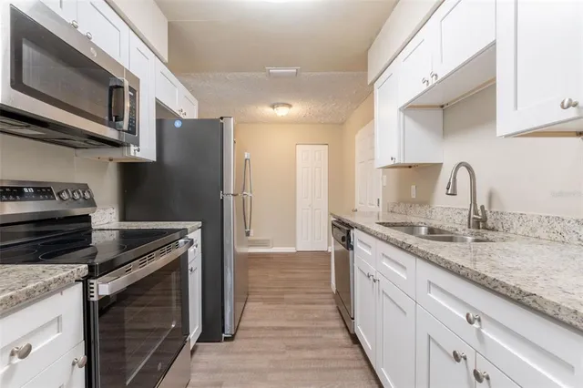 a kitchen with stainless steel appliances granite countertop a refrigerator and a stove top oven