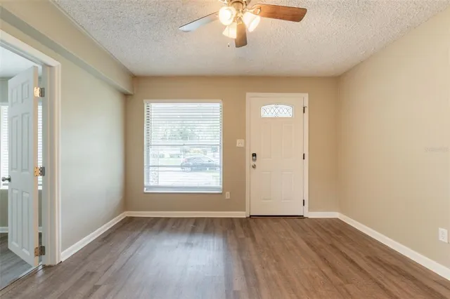 a view of an empty room with wooden floor and a window