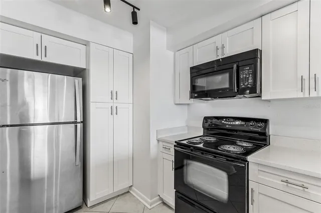 a kitchen with stainless steel appliances white cabinets white stove a microwave and a refrigerator