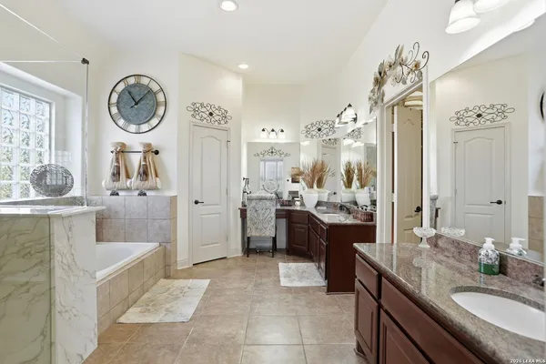 a large bathroom with a double vanity sink a toilet a mirror and a tub