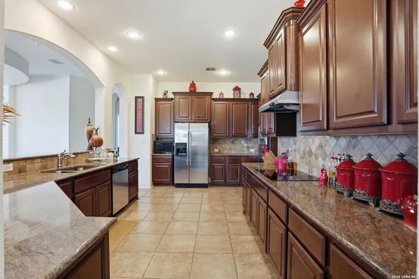 a large kitchen with stainless steel appliances granite countertop a sink stove and refrigerator