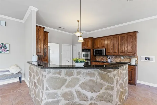 a kitchen with kitchen island granite countertop a stove a sink and a microwave
