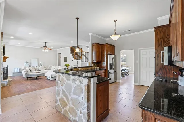 a kitchen with granite countertop a stove a sink a refrigerator and a fireplace