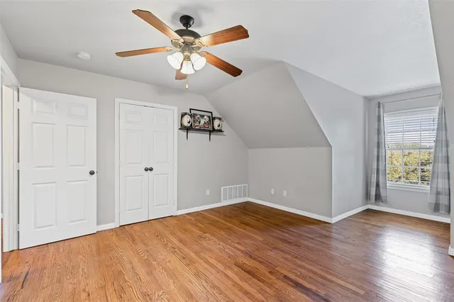 an empty room with wooden floor chandelier fan and windows