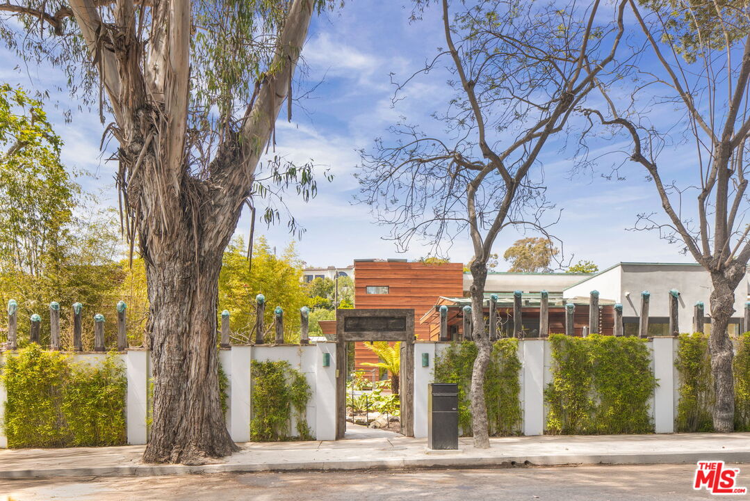 a view of a brick house with large trees and wooden fence