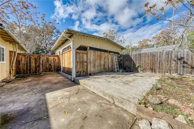 a view of a backyard with wooden fence and a large tree