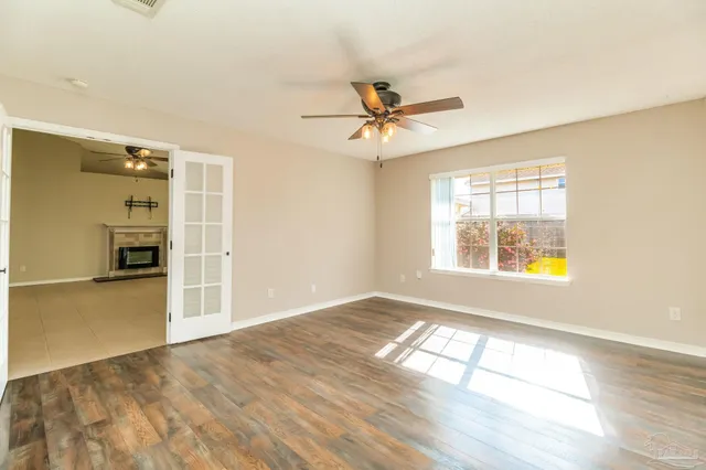 a view of empty room with wooden floor and fan