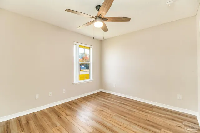 an empty room with a window and a ceiling fan