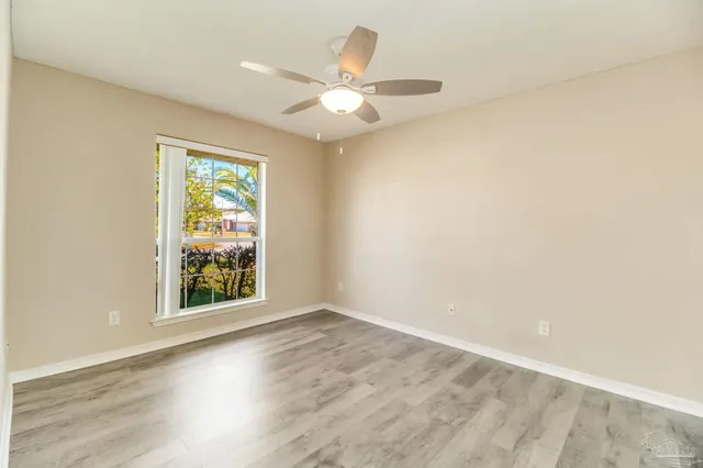an empty room with windows and ceiling fan