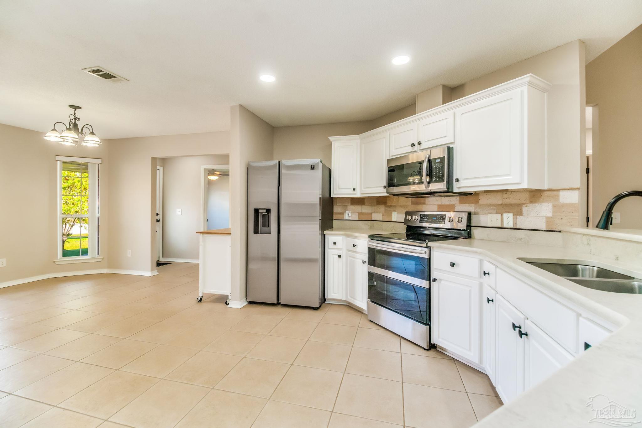 1225 Grand Ridge Circle Gulf Breeze, FL 32563 - Photo 9 of 29 a kitchen with stainless steel appliances granite countertop a refrigerator and a stove top oven