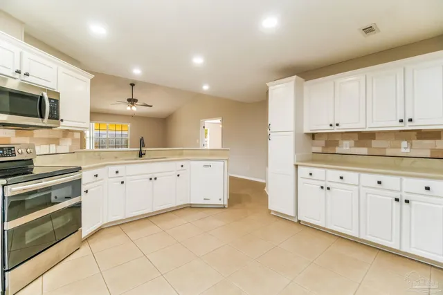 a kitchen with granite countertop white cabinets white stainless steel appliances with a sink and dishwasher