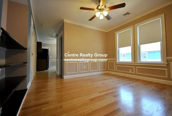 a view of an empty room with a window and wooden floor